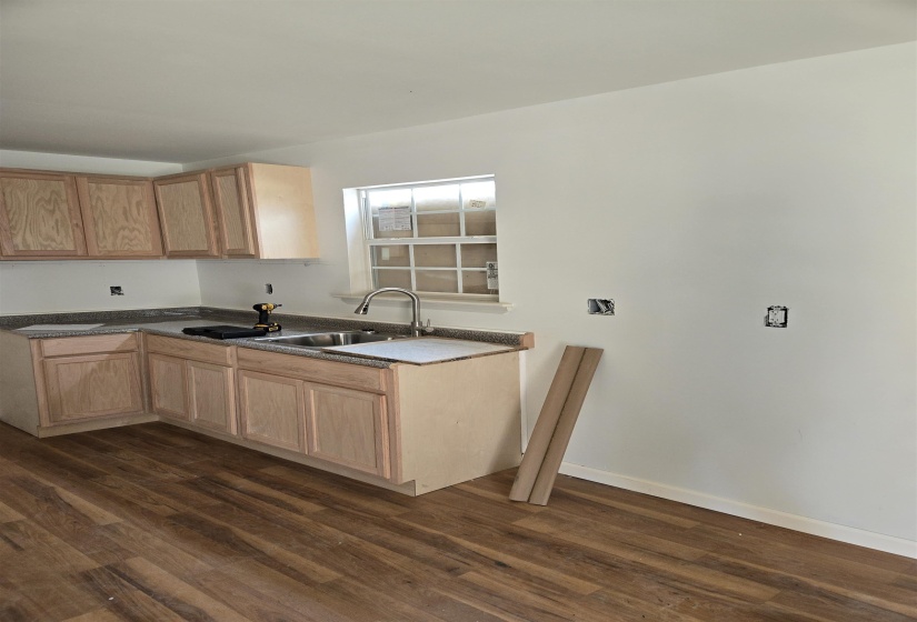 Kitchen with dark wood-type flooring and light wood finish cabinets