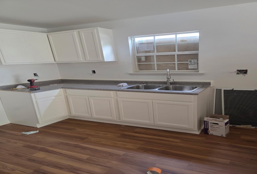 Kitchen with white cabinets, dark wood-style floors, and dark countertops