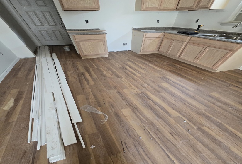 Kitchen with light wood finish cabinetry, dark wood finished floors, and dark countertops