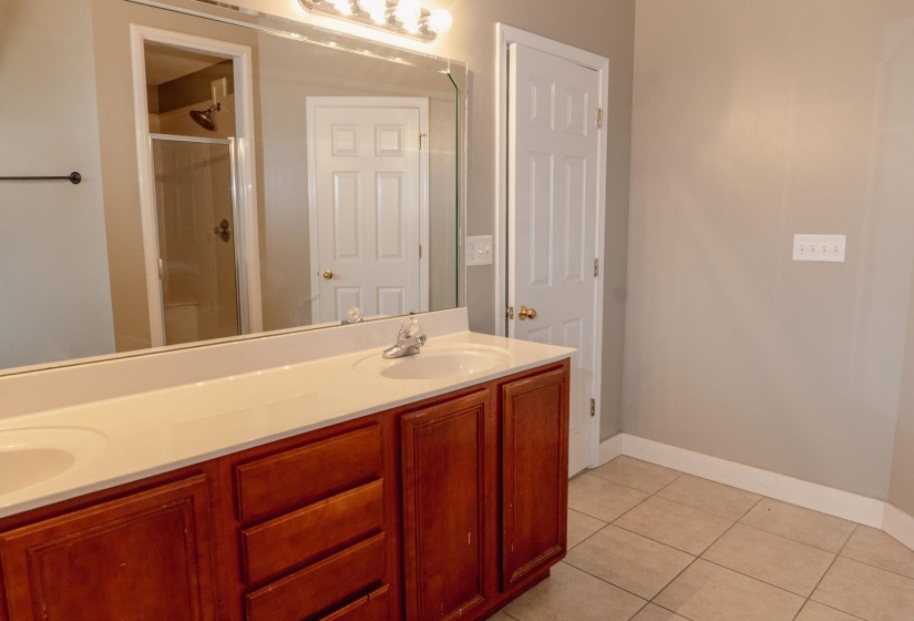 Full bath featuring double vanity, a stall shower, and light tile patterned floors