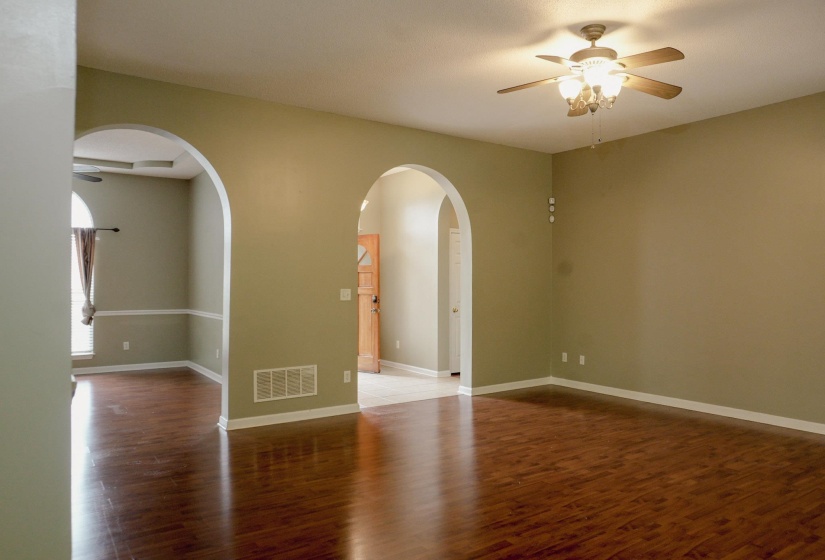 Empty room with a ceiling fan, dark wood-style floors, and arched walkways