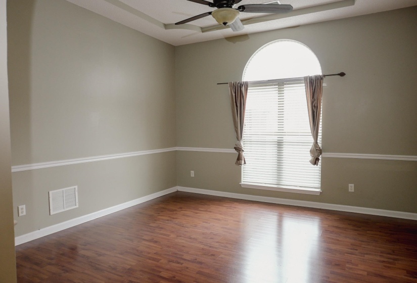 Spare room featuring a tray ceiling, ceiling fan, and dark wood-type flooring