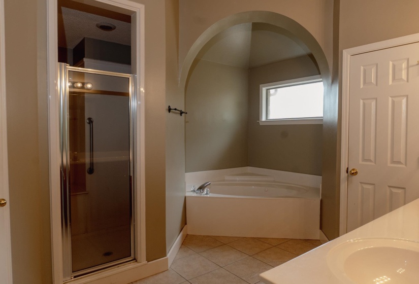 Full bath with a bath, a stall shower, light tile patterned floors, and double vanity