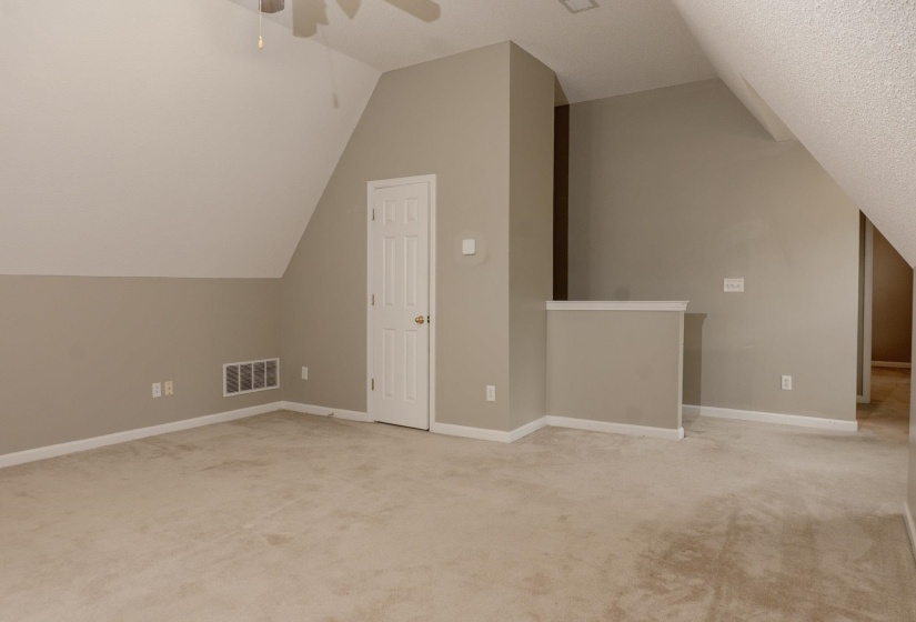 Bonus room with lofted ceiling, light colored carpet, and ceiling fan