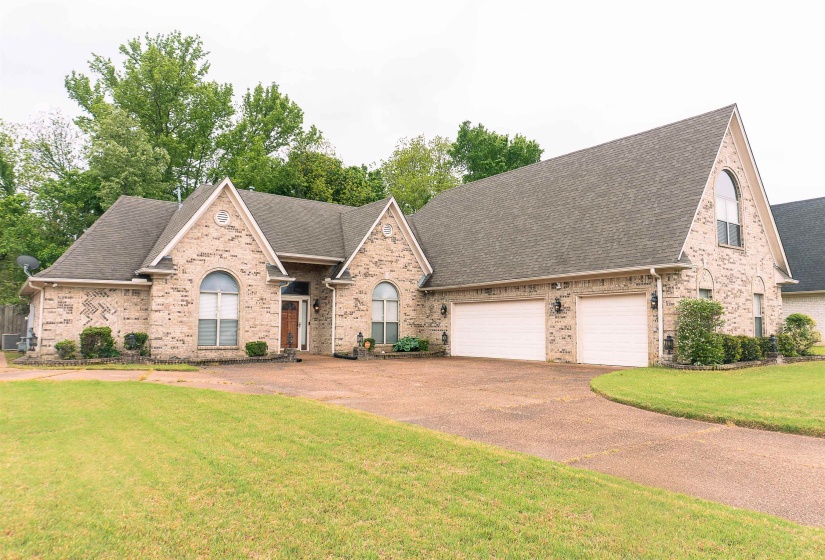 View of front of house with a shingled roof, an attached garage, brick siding, and driveway