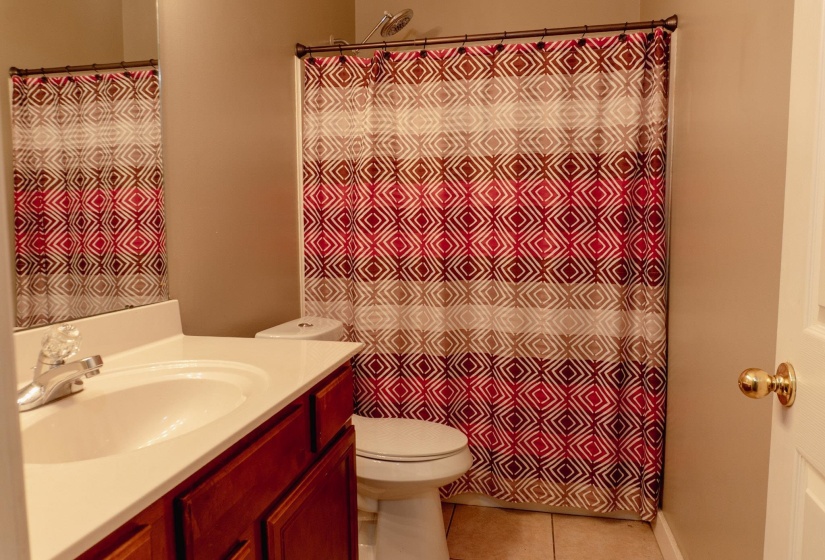 Full bathroom with vanity, light tile patterned floors, and curtained shower