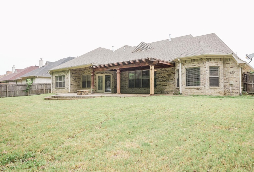 Rear view of house featuring a patio, a fenced backyard, and brick siding