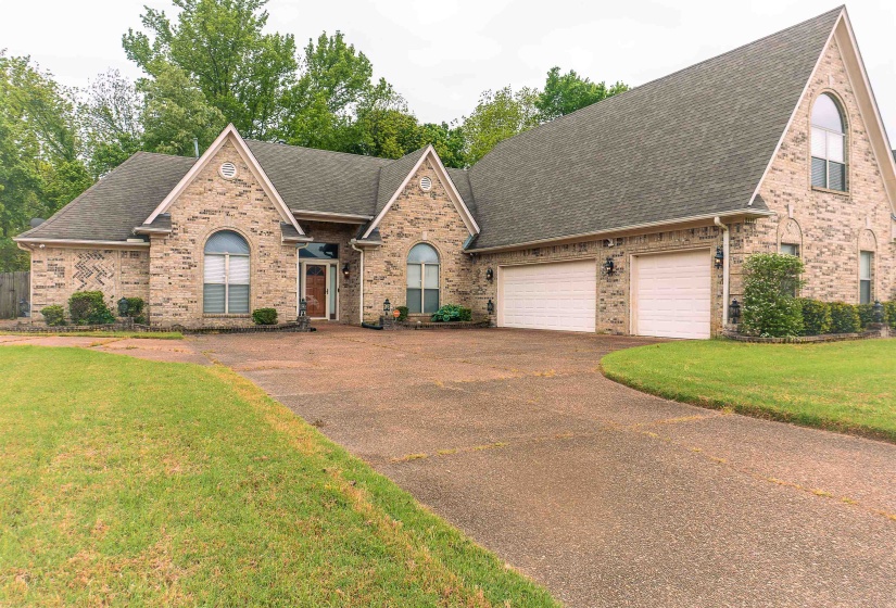 View of front of property featuring a shingled roof, asphalt driveway, an attached garage, and brick siding