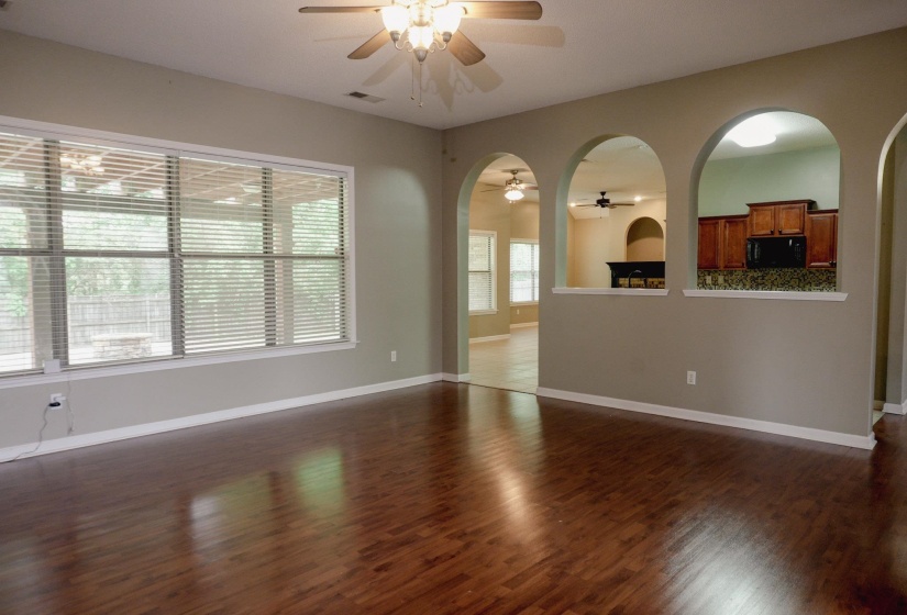 Unfurnished living room with a ceiling fan, dark wood-style flooring, and arched walkways
