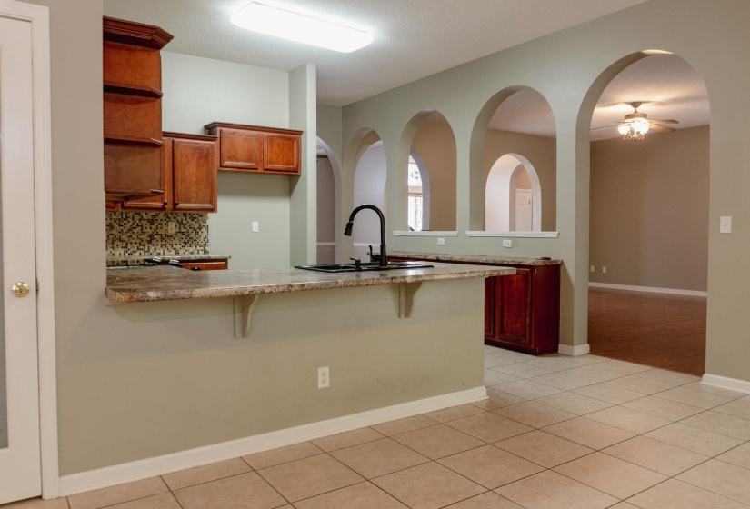 Kitchen featuring a peninsula, a kitchen bar, backsplash, and light tile patterned floors
