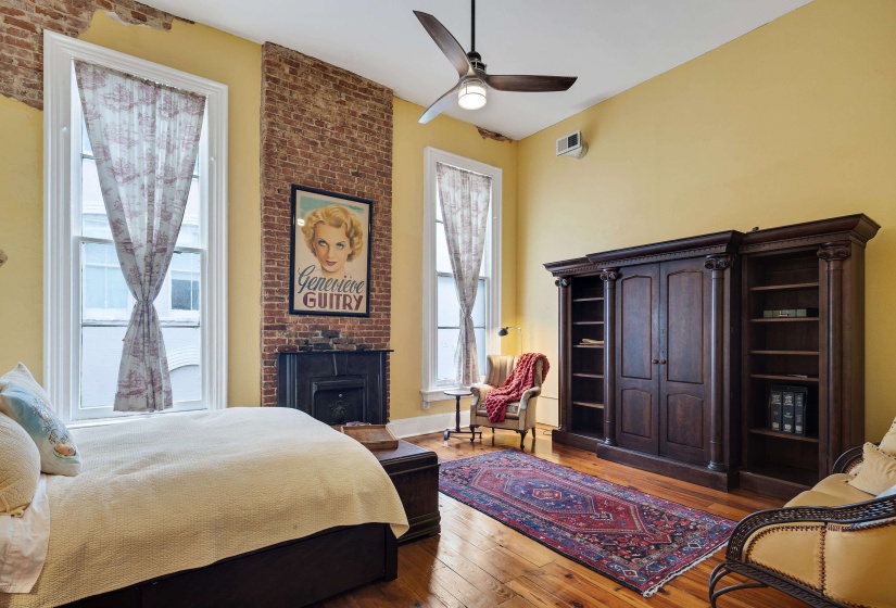 Bedroom with light wood finished floors, a ceiling fan, and a brick fireplace