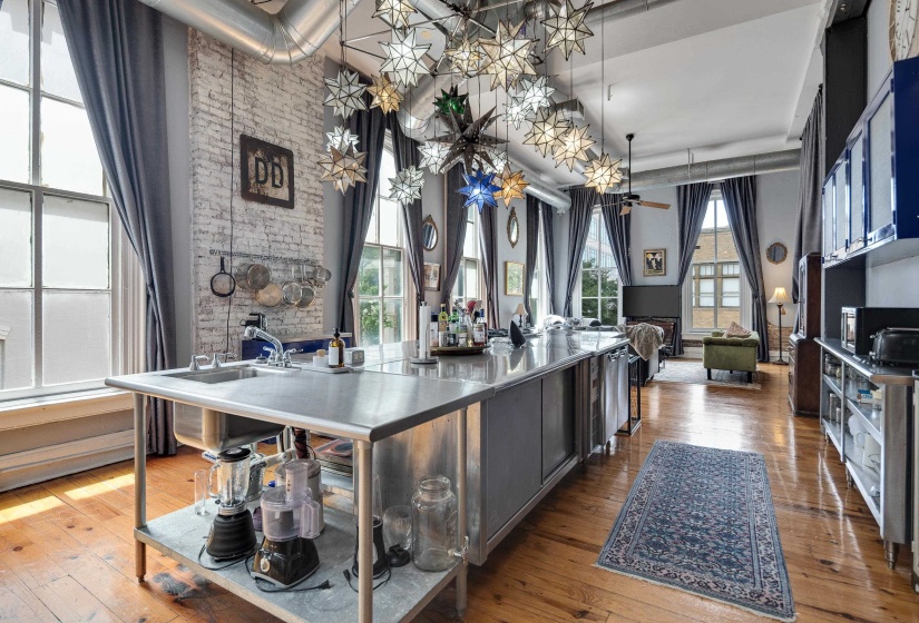 Kitchen with a spacious island, hardwood / wood-style floors, black microwave, and hanging light fixtures