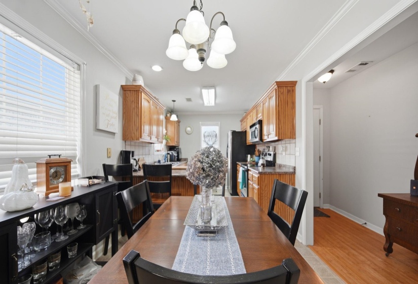 Dining room with ornamental molding, light wood-type flooring, and suspended lighting