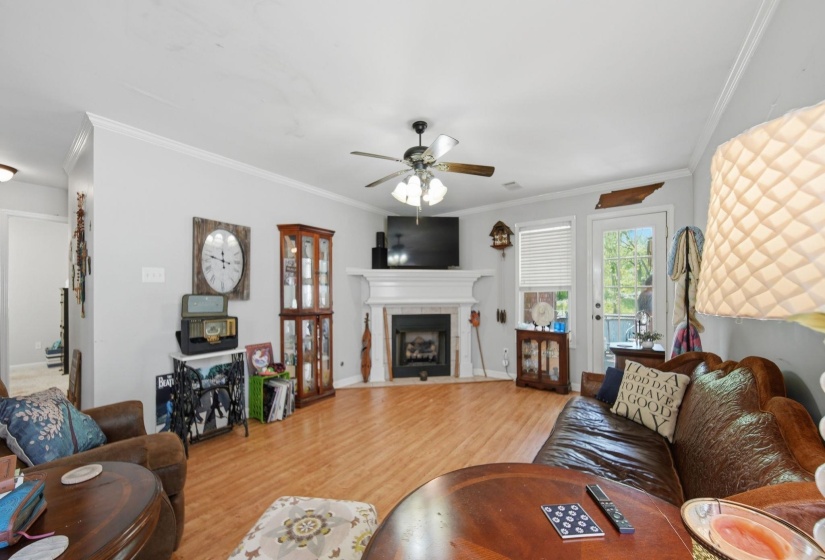 Living area featuring ornamental molding, wood finished floors, a ceiling fan, and a tile fireplace