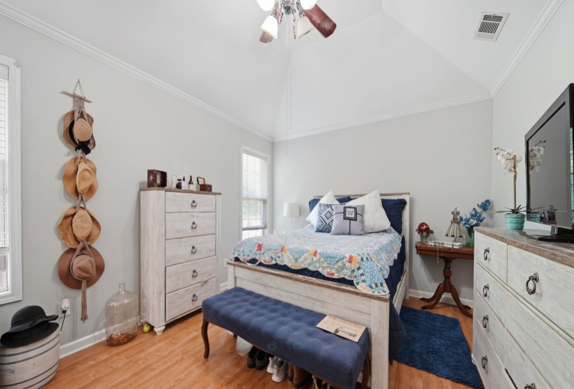 Bedroom with ornamental molding, light wood finished floors, lofted ceiling, and a ceiling fan
