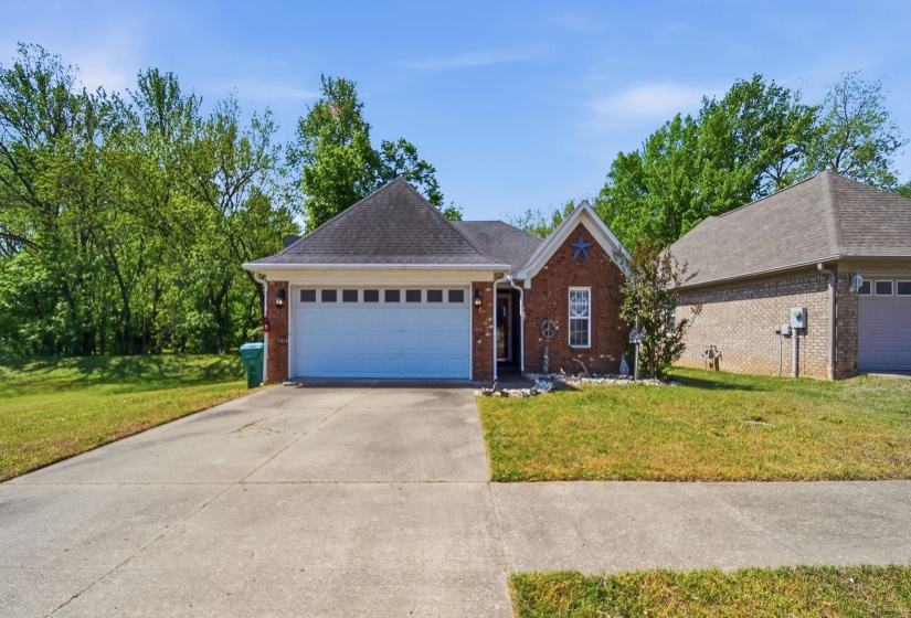 Ranch-style house featuring a front lawn, brick siding, a garage, and concrete driveway