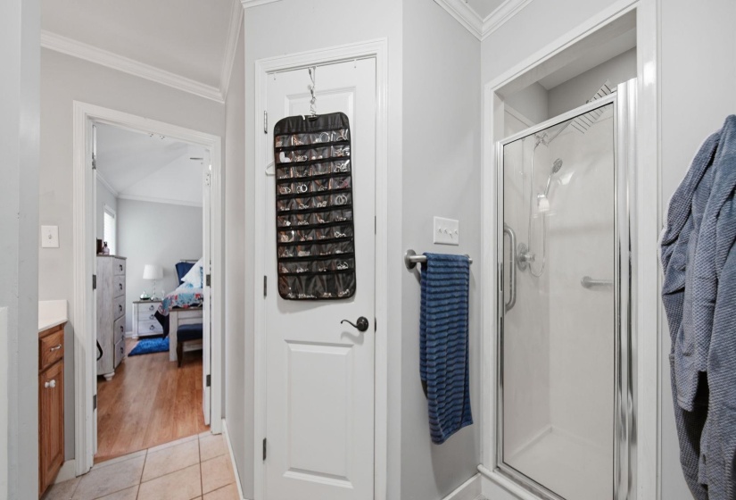 Bathroom featuring crown molding, ensuite bathroom, a shower stall, vanity, and light tile patterned floors