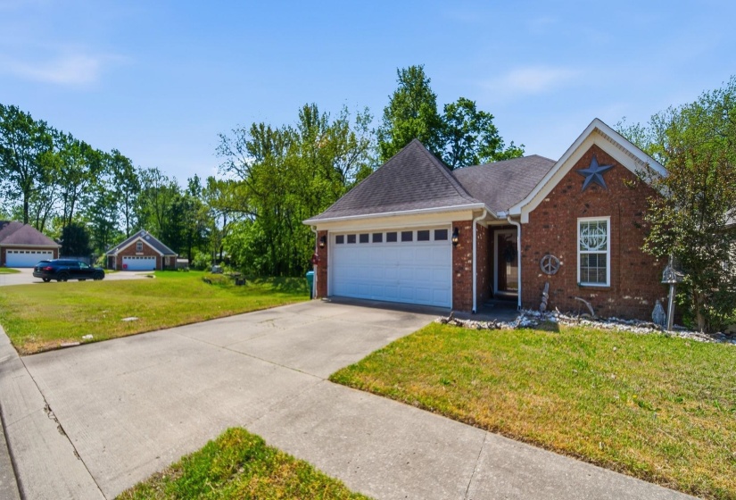 Ranch-style house with a front yard, a garage, brick siding, roof with shingles, and concrete driveway