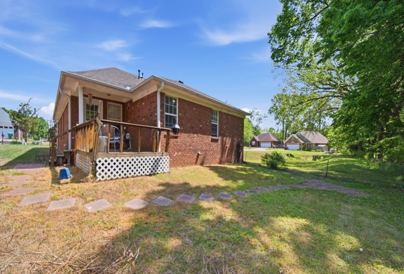 Rear view of house with brick siding, a lawn, and a deck