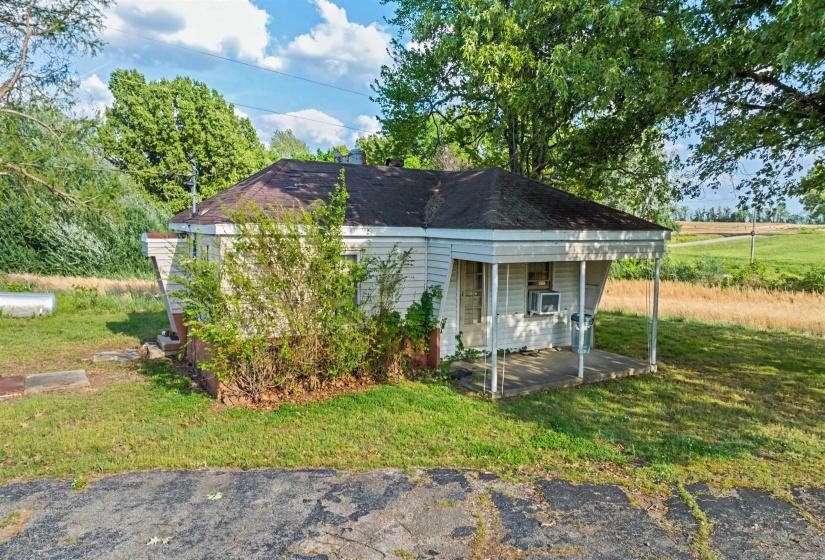 View of front of home featuring a front yard, a shingled roof, and a patio area