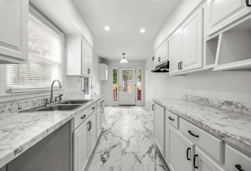 Kitchen featuring light countertops, light marble finish floors, white cabinets, recessed lighting, and a textured ceiling