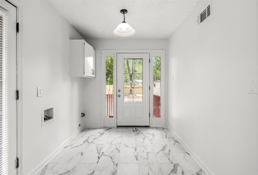 Doorway featuring marble look tiles and a textured ceiling