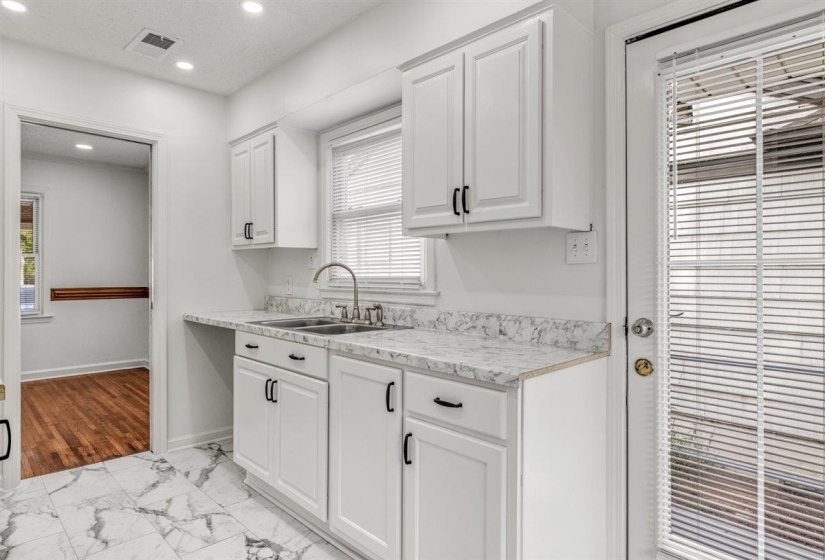 Kitchen featuring white cabinetry, light countertops, recessed lighting, and light marble finish floors