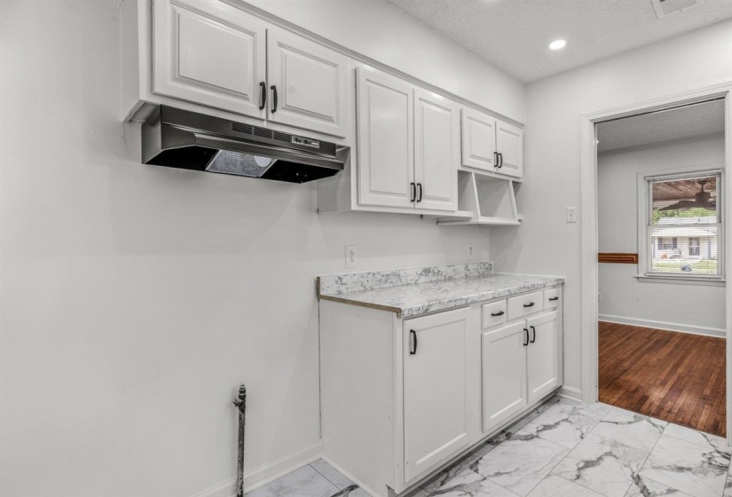 Kitchen with white cabinets, light countertops, light marble finish floors, recessed lighting, and a textured ceiling