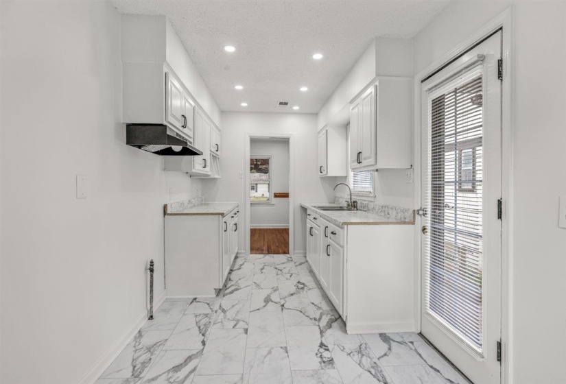 Kitchen featuring white cabinets, light countertops, recessed lighting, a textured ceiling, and light marble finish flooring