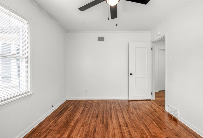 Empty room featuring dark wood-style flooring, ornamental molding, and ceiling fan