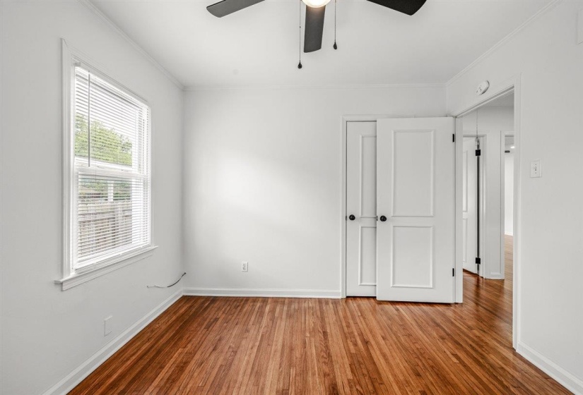 Unfurnished bedroom with wood finished floors, ornamental molding, and ceiling fan