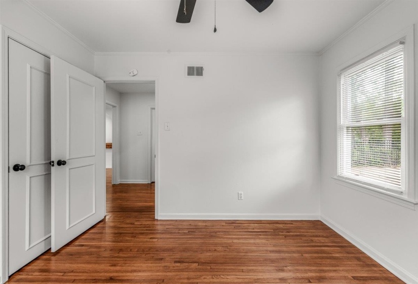 Unfurnished bedroom with dark wood-style floors, ornamental molding, and a ceiling fan
