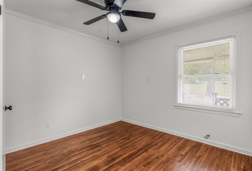 Empty room featuring crown molding, dark wood-style flooring, and ceiling fan