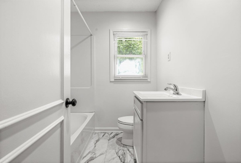 Bathroom featuring vanity, light marble finish flooring, and shower / bathtub combination