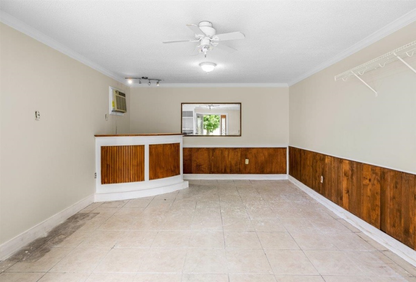 Unfurnished room with wooden walls, ceiling fan, a textured ceiling, light tile patterned floors, and ornamental molding