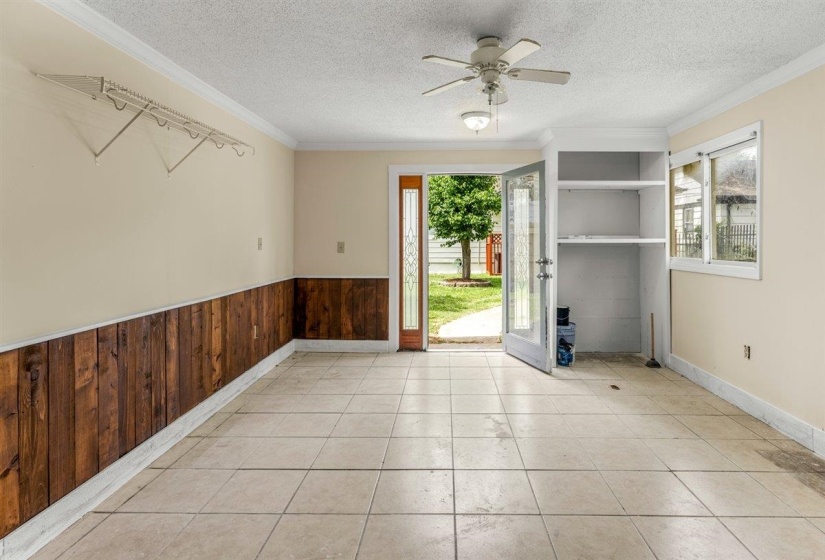 Spare room with wood walls, a textured ceiling, a ceiling fan, plenty of natural light, and crown molding