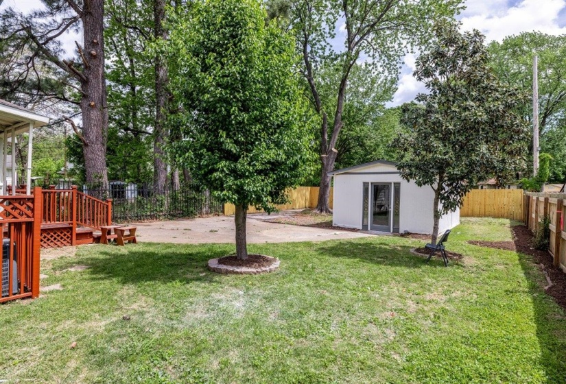 Fenced backyard with a wooden deck, a storage shed, and a patio