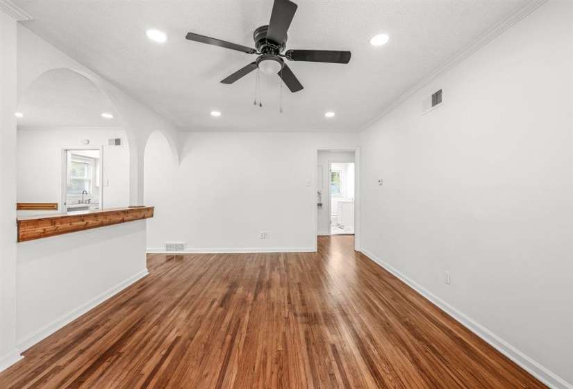 Unfurnished living room with ceiling fan, dark wood-style floors, arched walkways, recessed lighting, and crown molding