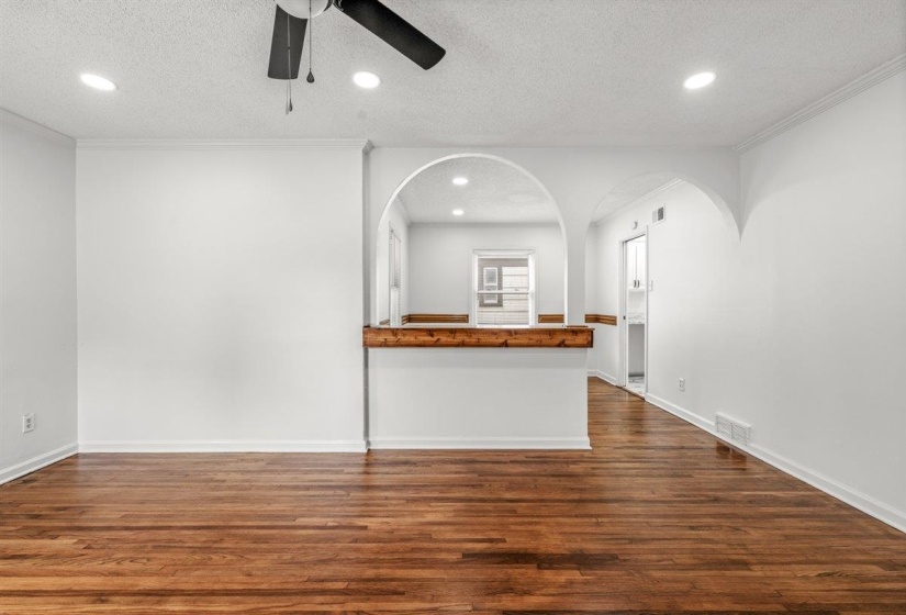 Unfurnished living room featuring a ceiling fan, a textured ceiling, dark wood-style floors, recessed lighting, and arched walkways