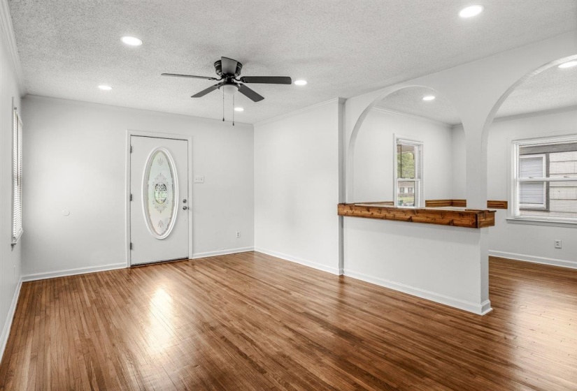 Unfurnished living room with ceiling fan, a textured ceiling, recessed lighting, dark wood-type flooring, and ornamental molding