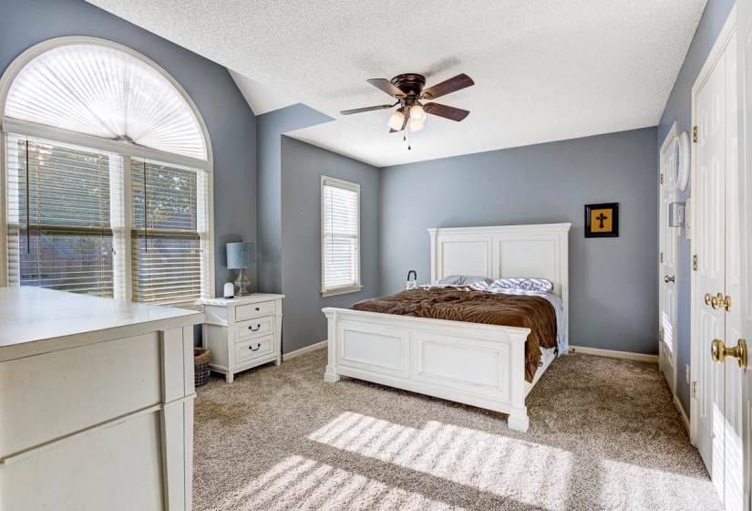 Bedroom with light carpet, ceiling fan, and a textured ceiling