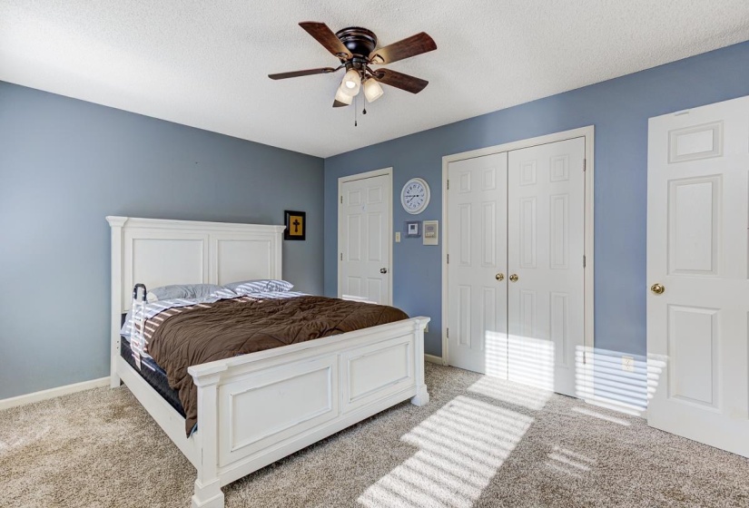 Carpeted bedroom with a closet, ceiling fan, and a textured ceiling