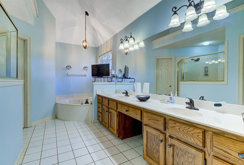 Full bathroom featuring double vanity, a chandelier, light tile patterned flooring, a bath, and a stall shower