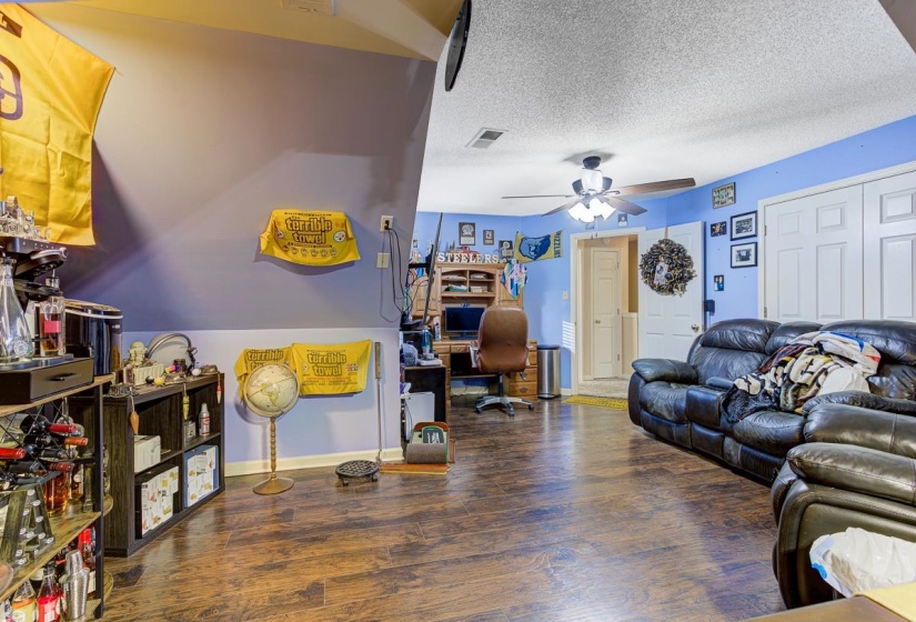 Living room with a desk, dark wood finished floors, a textured ceiling, and ceiling fan