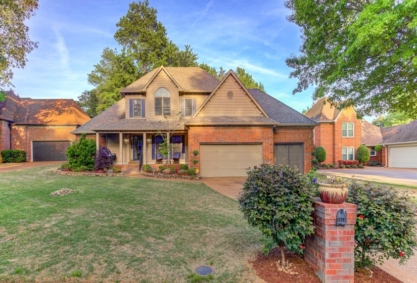 Traditional home featuring a porch, a shingled roof, brick siding, a front yard, and driveway