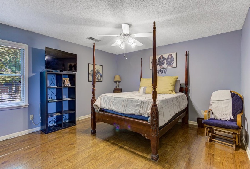 Bedroom with a textured ceiling, wood finished floors, and a ceiling fan