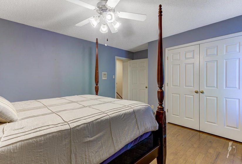 Bedroom featuring light wood-style flooring, a textured ceiling, a ceiling fan, and a closet