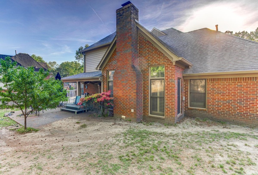 Back of property with brick siding, roof with shingles, covered porch, and a chimney