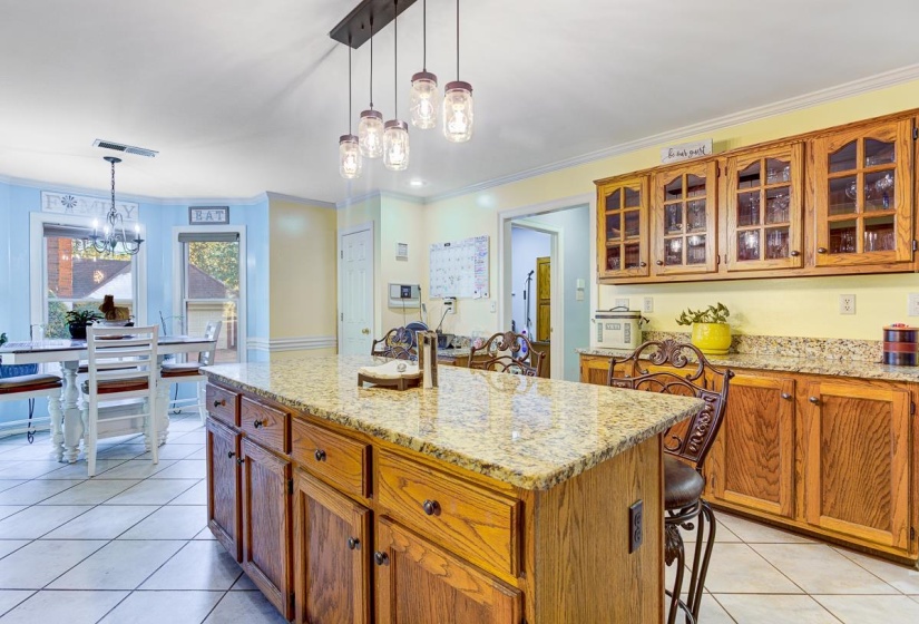 Kitchen with a center island, light stone counters, wood finish cabinets, and crown molding
