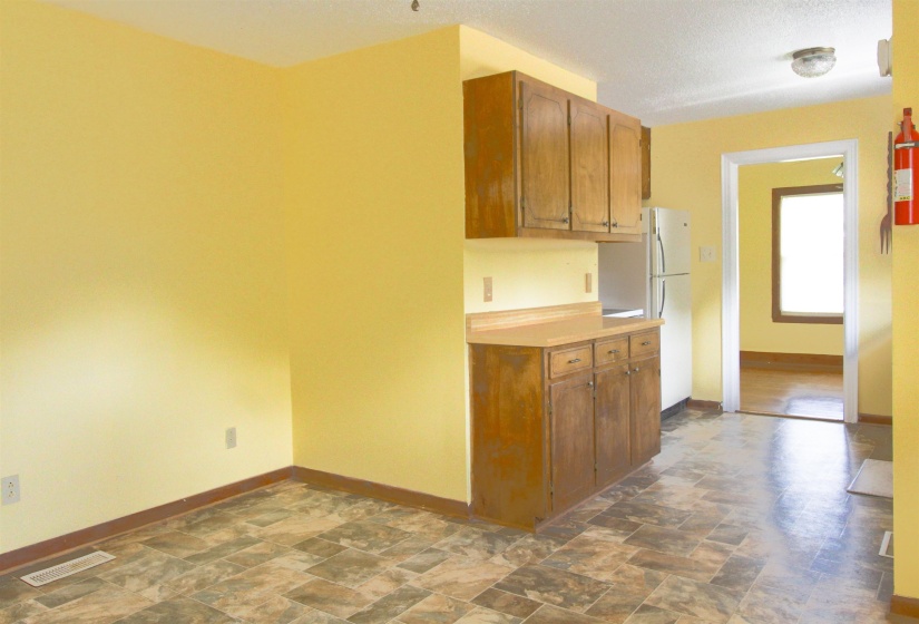 Kitchen with stone finish floors, light countertops, wood finish cabinetry, and freestanding refrigerator